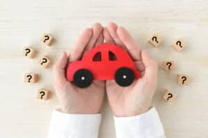 Red Toy Car in Hands with Question Marks Around It